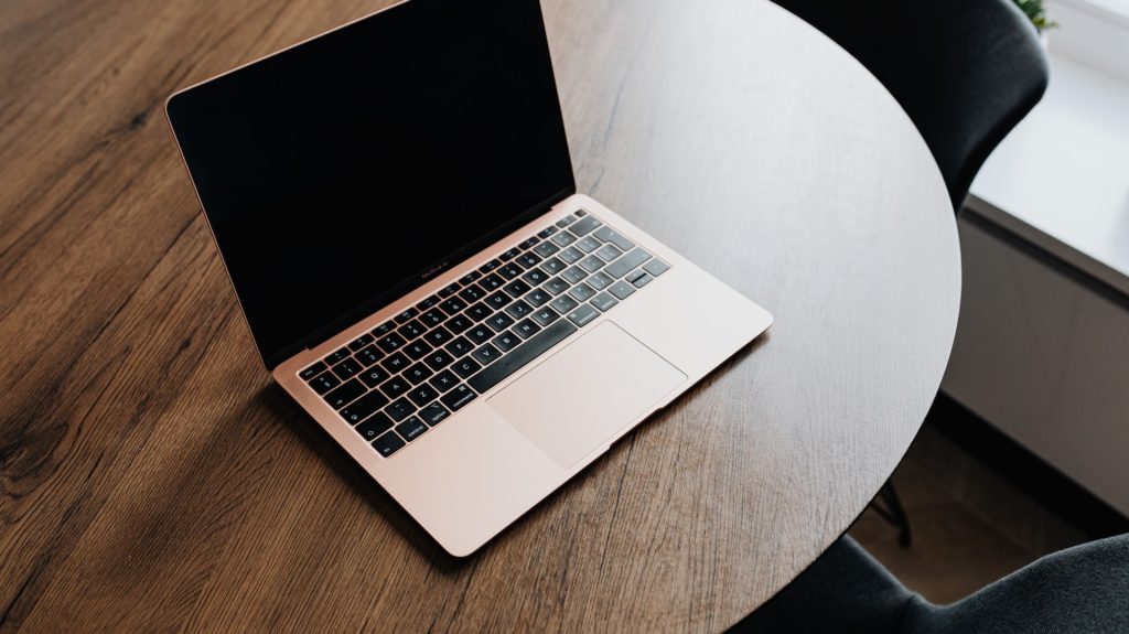 Open Macbook computer sitting atop wooden table