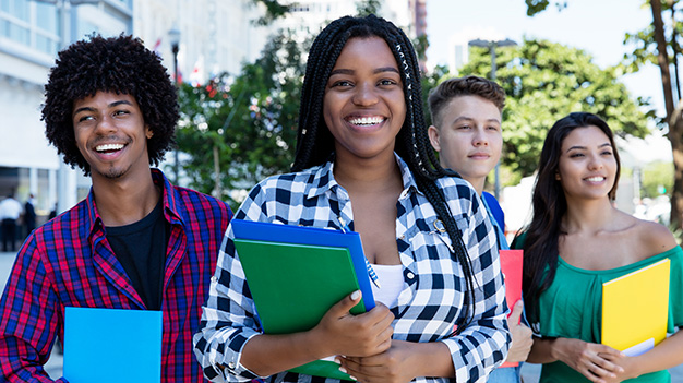 Group of IT students standing together outside with books in hand