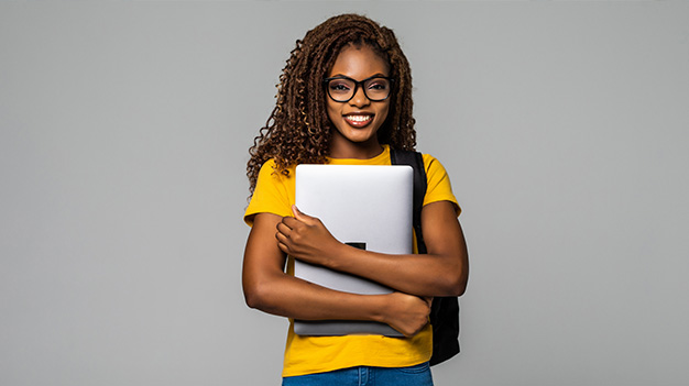 Female student wearing a yellow top holding laptop in her arms