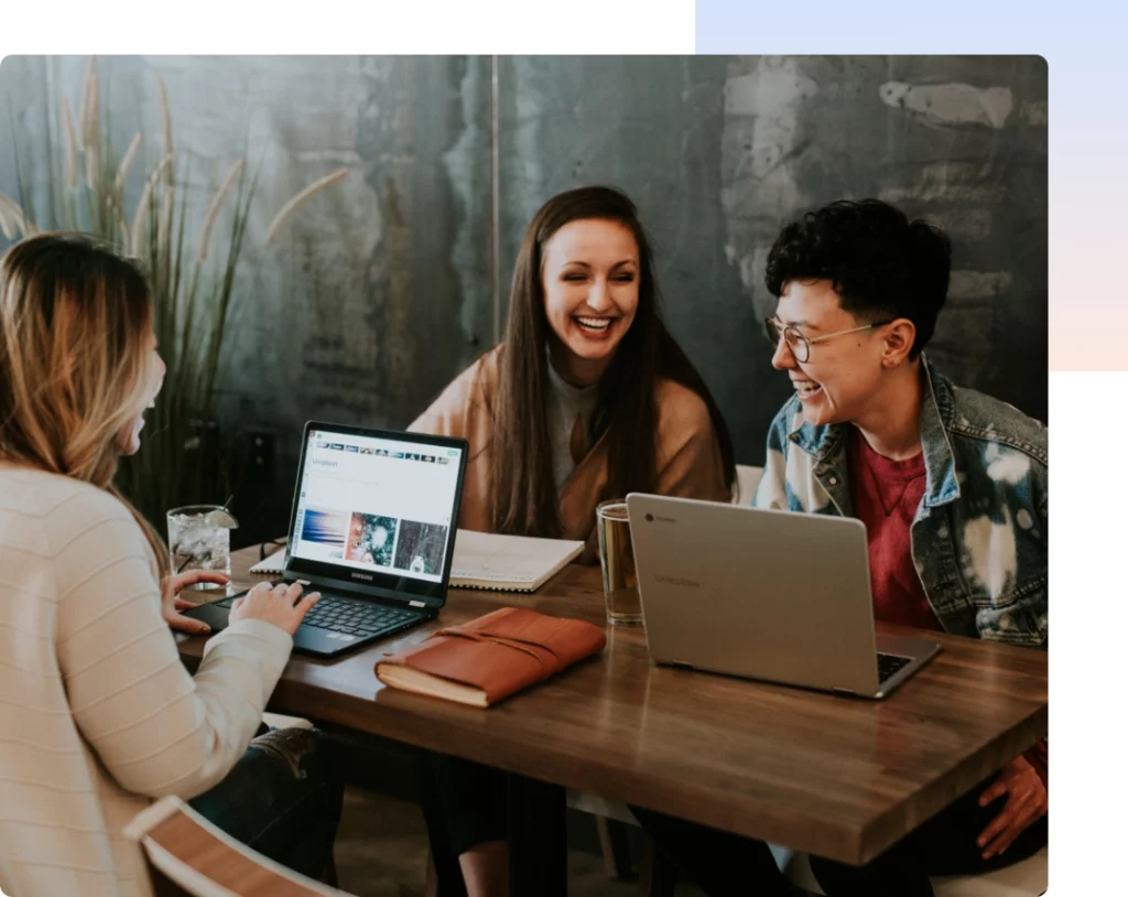 Students sitting at a desk doing work and conversing