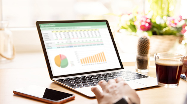 Person working on laptop computer with analytical graphs on screen