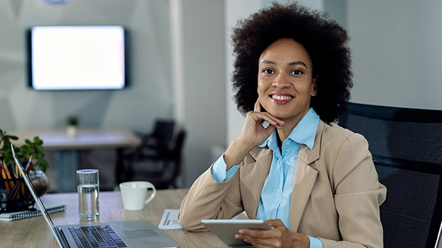African business woman sitting at office desk smiling