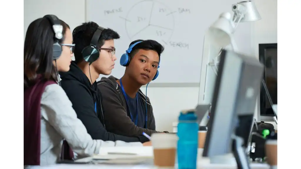 Students in classroom with headphones on working at computers